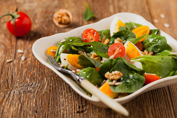 Delicious salad of fresh spinach, boiled egg, tomatoes, nuts and sunflower seeds