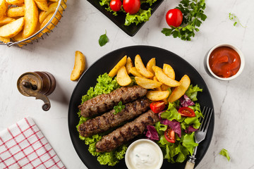 Traditional cevapcici served with baked potatoes. Flat lay. Stone background.