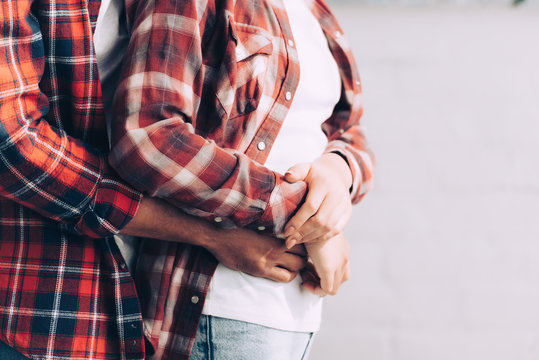 cropped image of man in checkered shirt hugging girlfriend from behind at home