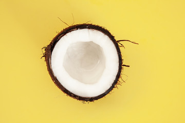 one half of ripe coconut on yellow background,top view