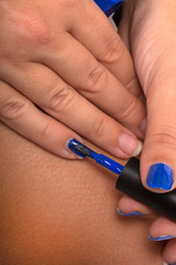 mani femminili che applicano lo smalto per unghie blù