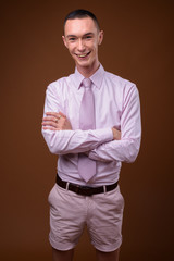 Young handsome androgynous businessman against brown background