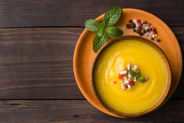 Pumpkin soup mashed with spices in wooden bowls on dark boards.