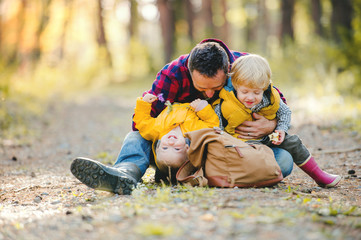 A mature father with backpack and toddler son in an autumn forest.