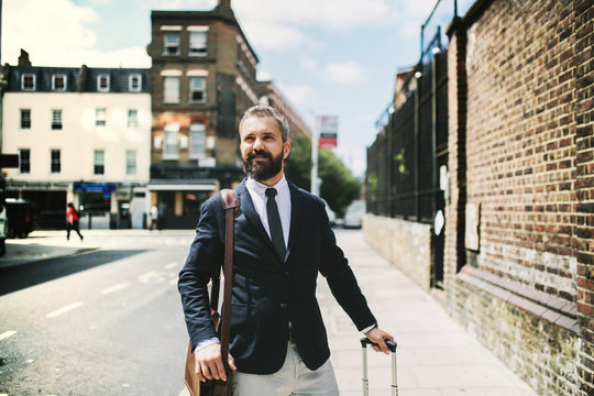 Hipster Businessman With Suitcase Walking Down The Street In London.