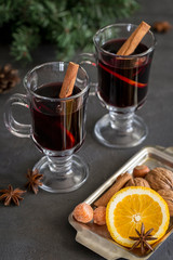 Mulled wine in glass with spices at dark background
