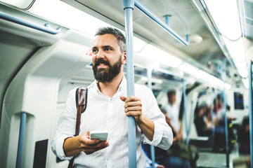 Hipster businessman with smartphone inside the subway in the city, travelling to work. © Halfpoint