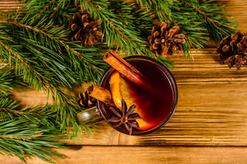 Cup of mulled wine with cinnamon and fir tree branches on wooden table. Top view