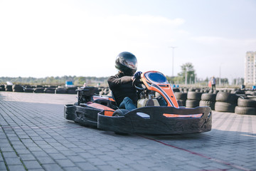 Go-Kart racing car on the track in action, championship, active sports, extreme fun, the driver keeps his hands on the wheel. driver protective gear. day, karting