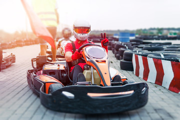Go-Kart racing car on the track in action, championship, active sports, extreme fun, the driver keeps his hands on the wheel. driver protective gear. day, karting - obrazy, fototapety, plakaty