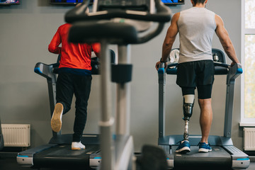 Fototapeta na wymiar rear view of sportsmen running on treadmills at gym