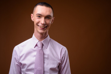 Young handsome androgynous businessman against brown background
