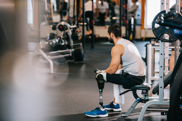 Fototapeta na wymiar overworked sportsman with artificial leg sitting at gym