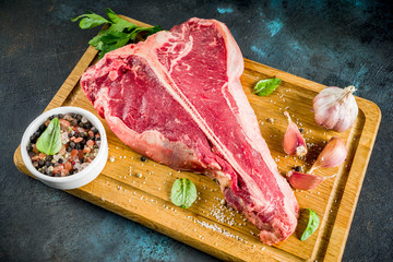 Raw fresh meat, t-bone beef steak with spices and herbs on cutting board