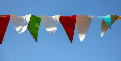 Fototapeta na wymiar Festive multi-colored flags on a background of blue sky