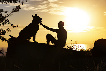 silhouette of man and dog enjoying beautiful landscape , boy with pet at sunset, concept of harmony human and nature, happiness