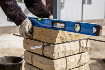 The worker is laying bricks on the fence