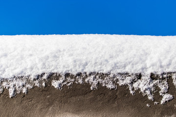 Snow on concrete against a blue sky