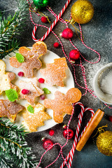 Creative idea for xmas breakfast, funny christmas pancakes in form of gingerbread man, christmas tree and star, dark concrete background with xmas decorations, top view