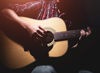 GUITARIST PLAYS ON THE ACOUSTIC GUITAR ON THE STAGE.