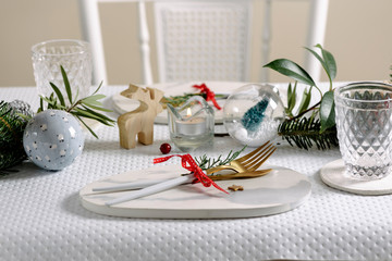 Holiday celebration table setting, marble dish and golden cutlery. white and gold colors