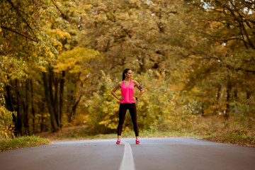Fototapeta premium Young woman have a break during training in the autumn forest