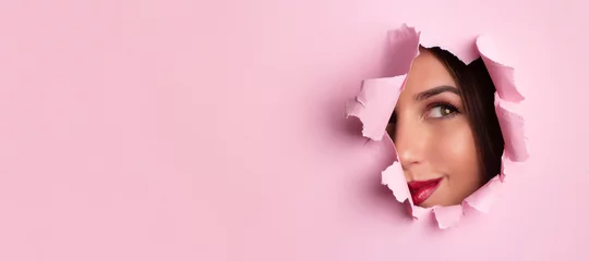 Printed roller blinds Beauty salon Beauty salon advertising banner with copy space. Beautiful girl looks through hole in pink paper background. Make up artist, fashion, beauty concept. Cosmetics sale.