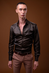 Fototapeta premium Young handsome androgynous businessman against brown background