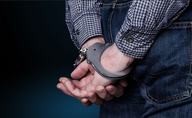 Cropped image of male hands in handcuffs behind his back