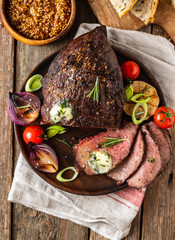 Roast beef on cutting board. Wooden background. Copy space.