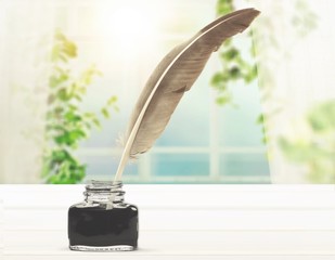Feather quill pen and glass inkwell isolated on a white