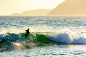 Silhouette of surfer on the beach, by the sea in Ipanema, Rio de Janeiro during sunset