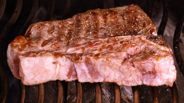 UHD closeup shot of the seasoned t-bone steak on a barbecue grill
