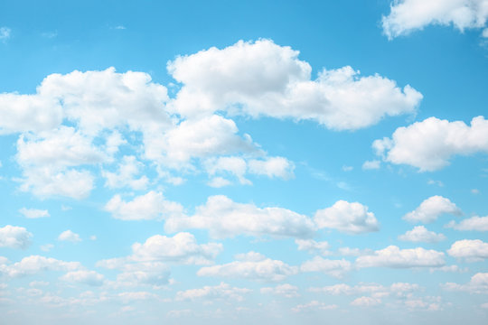 White Fluffy clouds in the light blue sky. Gradient Celestial Azure background. 