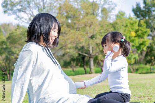 妊娠した臨月のお母さんと公園で糸電話で遊ぶ幼い女の子 家族 親子 妊娠 妊婦 愛 幸せイメージ Wall Mural Chikala