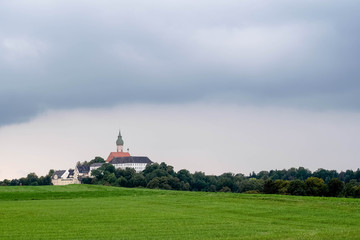 Klosterkirche hinter grüner Wiese mit Wolkenhimmel