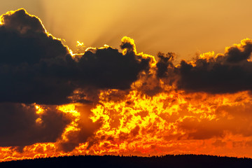 The evening sky the setting sun, the rays from the sun diverge in the sky, sky clouds atmosphere in the evening, scarlet zakat