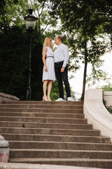 Beautiful cuple stand on the stairs and hug each other. Man and woman walking in the park. LoveStory