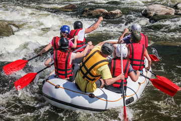 Group of men and women, enjoy water rafting activity at river. Extreme rafting.