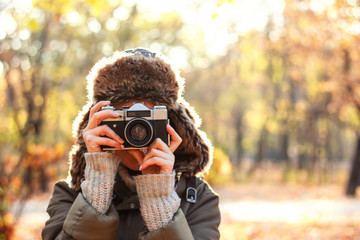 Fototapeta premium Young woman taking pictures in the autumn park. Concept girl photographer