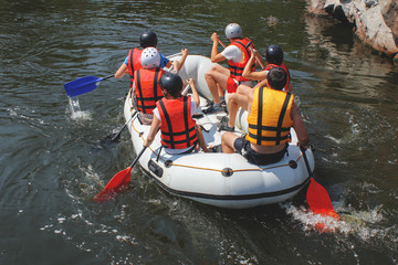 Group of men and women, enjoy water rafting activity at river. Rafting family on holidays