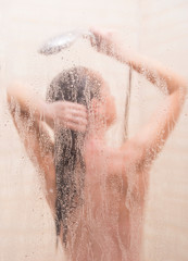 The girl in the shower behind the misted glass takes water treatments.
