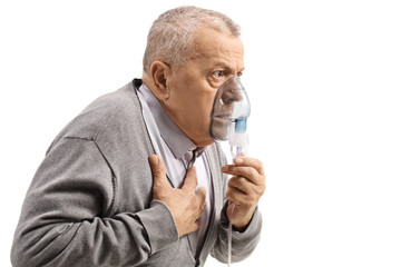 Elderly man with astma using an inhaler and holding his chest