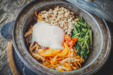 Close-up of Homemade Bibimbap rice in pot,on old wood table background.