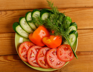 Cucumbers, tomatoes, peppers and dill cut into pieces on a plate.