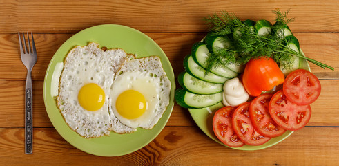 Fried eggs, pieces of vegetables, bread and fork on the table.