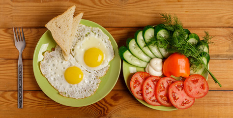 Fried eggs, pieces of vegetables, bread and fork on the table.