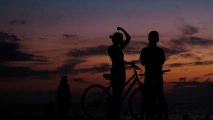 Fototapeta na wymiar Silhouette of tourist photographing on the smartphone sunset on the sea