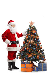 Santa Claus decorating a Christmas tree and looking at the camera