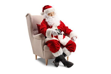 Santa Claus sitting in an armchair and holding a remote controller